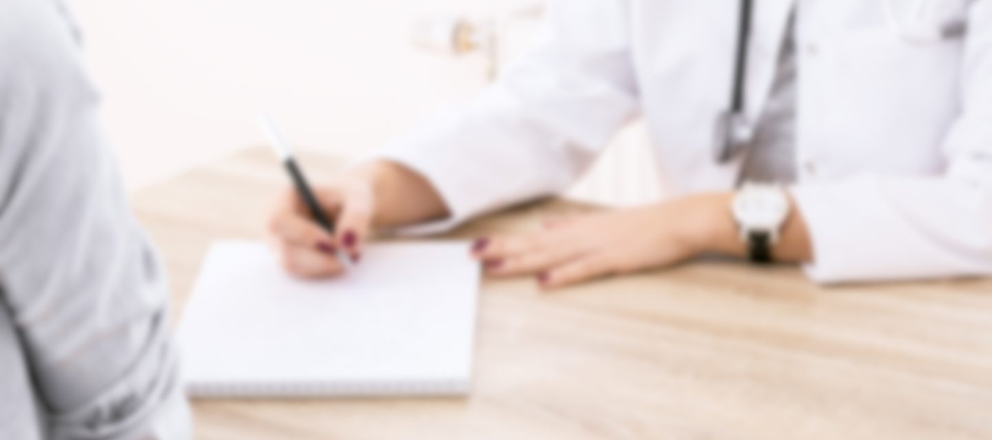 Blurry image of doctor writing while seeing patient.