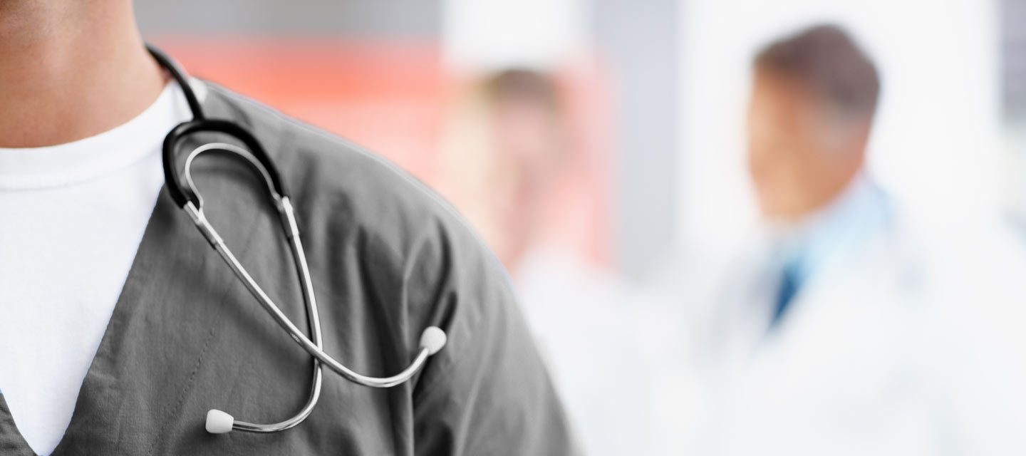 Closeup of man in gray Avala scrubs with name-tag and stethoscope.